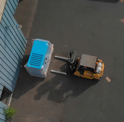arial-view-of-a-yellow-forklift-moving-a-blue-Rogers-Machinery-compressed-air-equipment