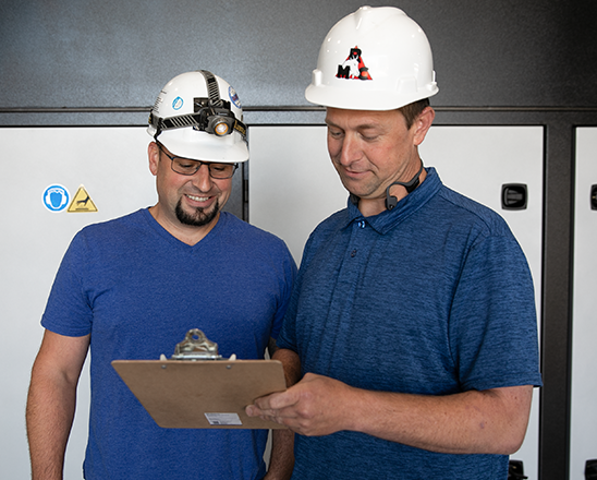 Rogers-Machinery-repair-expert-wearing-a-blue-shirt-while-at-a-customer-site-performaning-critical-air-compressor-maintenance-on-the-white-air-compressor