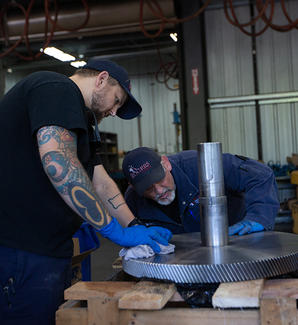 Two-Rogers-Machinery-compresssed-air-expertswearing-blue-hats-repairing-silver-blower-bearings-for-a-blower-repair