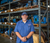Rogers-Machinery-Company-compressed-air-expert-earing-a-blue-uniform-standing-with-hands-clasped-in-front-of-warehouse-shelves-with-blower-systems-in-the-background